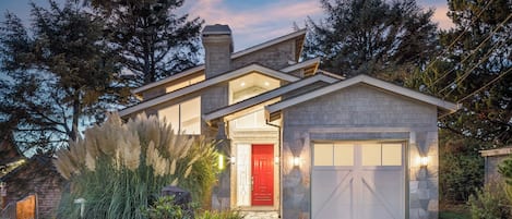 A modern house with a stone facade, a red door, and a garage.