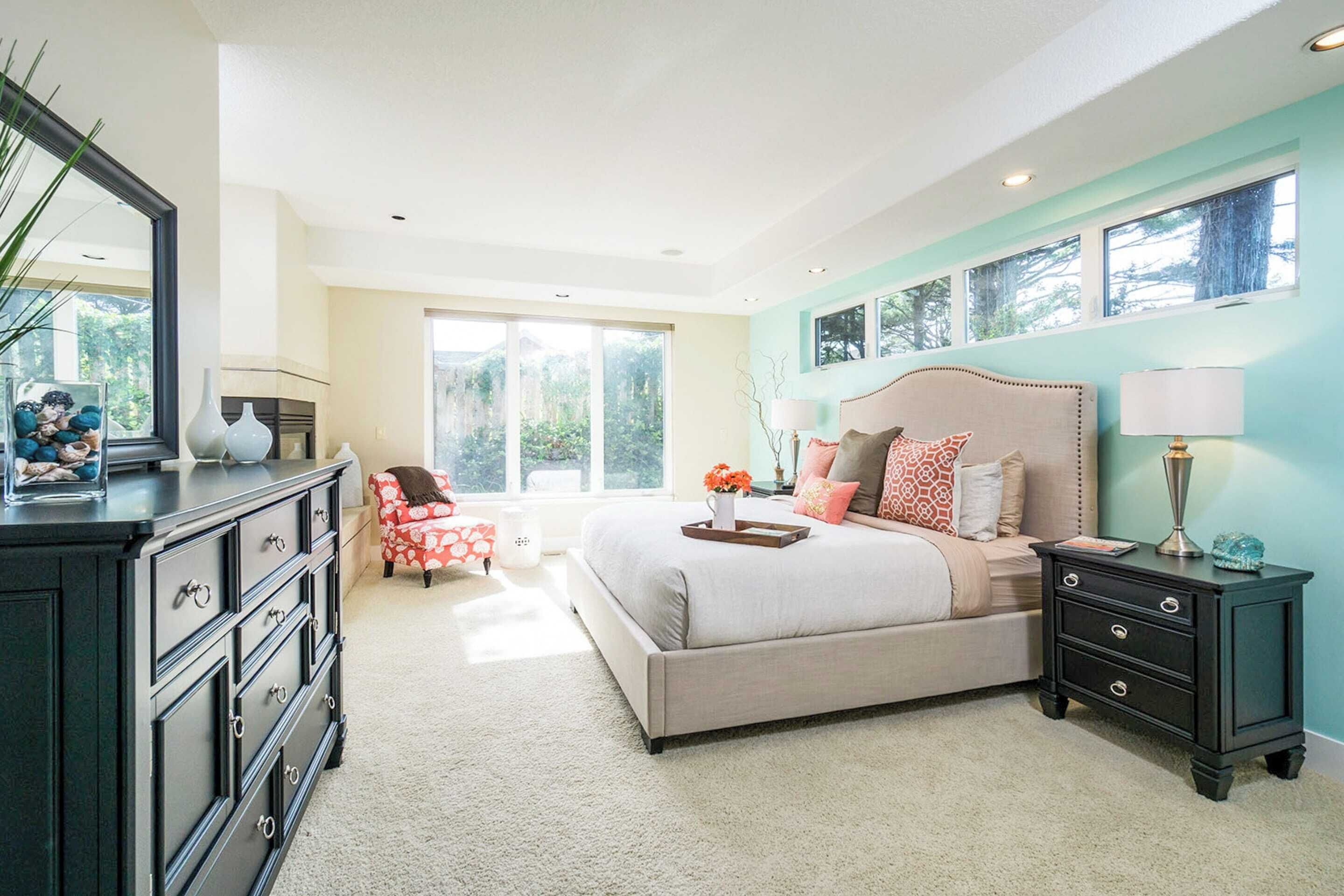 A bedroom with a large bed, a dresser, a nightstand, and a chair.