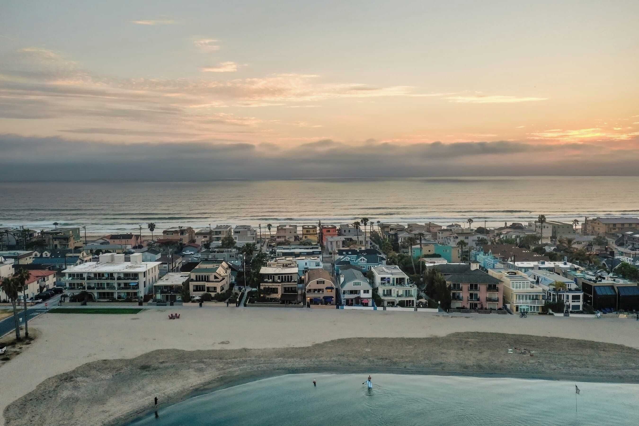 A coastal town with buildings along the beach and a view of the ocean.