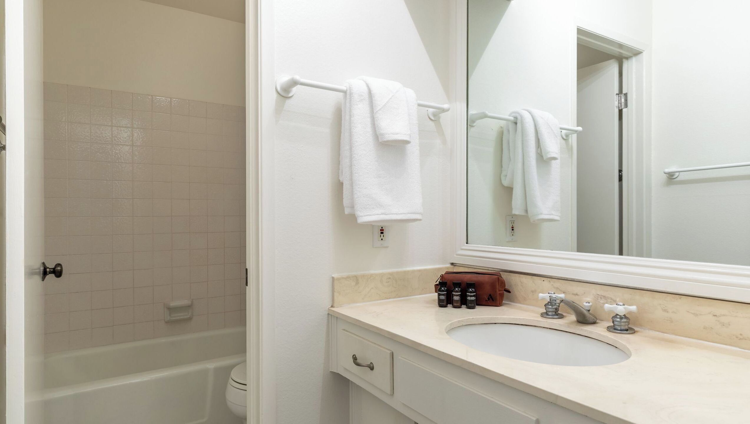 A bathroom with a bathtub, a sink, a mirror, and a towel rack.