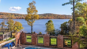 A swimming pool with a view of a lake and hills in the background.