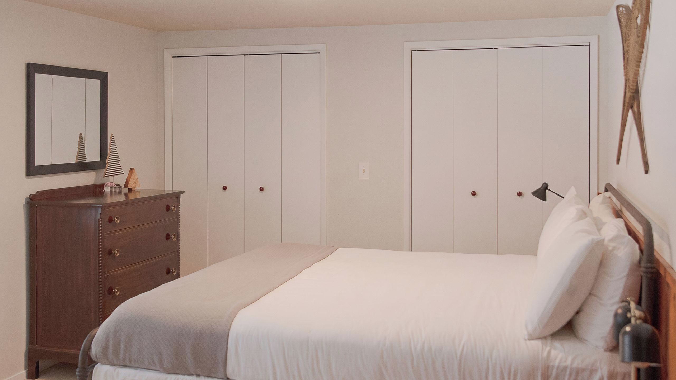 Een slaapkamer met een bed, een dressoir en twee kledingkasten.