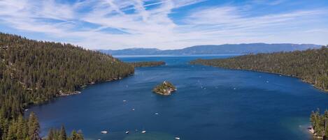 Un lago rodeado de un bosque tupido, con barcos en el agua y una pequeña isla en el centro.