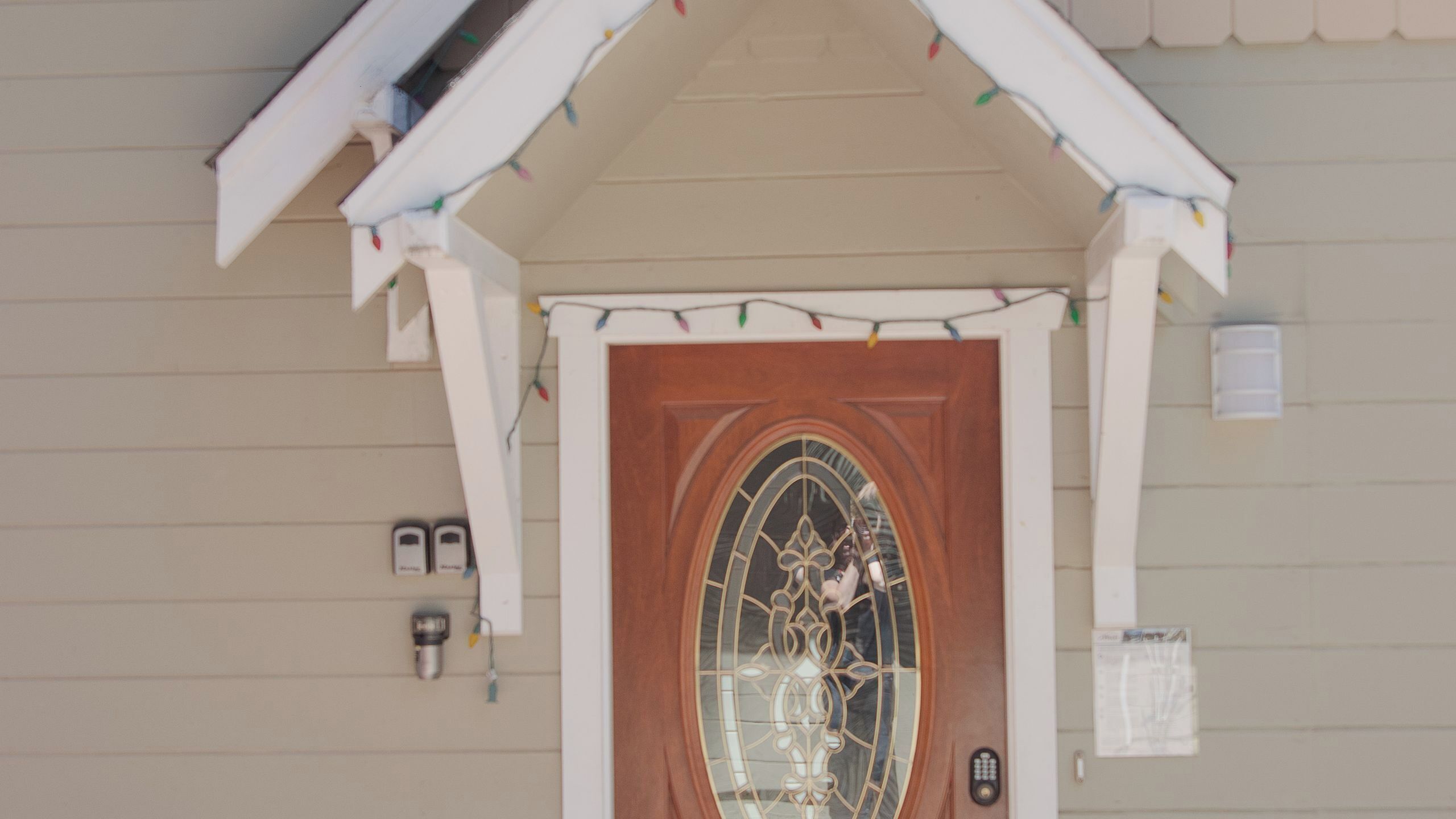 Une maison avec une porte en bois, une fenêtre ornée de motifs décoratifs en verre et une petite boîte aux lettres fixée au mur.