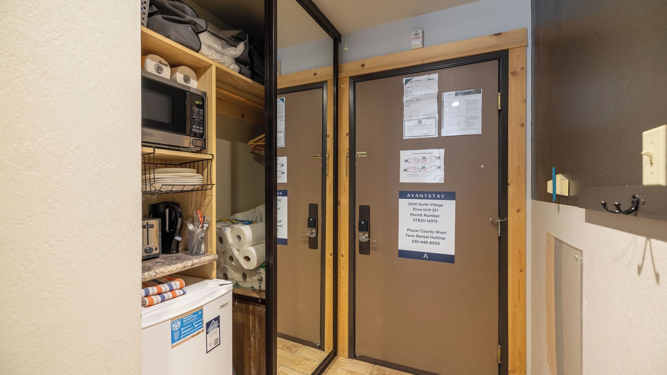 A kitchenette with a microwave, toaster, and coffee maker, and a door with an AVANTSTAY sign.