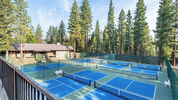 A tennis court with multiple courts, surrounded by tall trees and a lodge with a thatched roof. - Flurry by Avantstay Tahoe Donner Home w/ Access to Northstar Resort Community (Truckee)