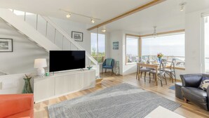A spacious living room with a staircase, a dining area, and a balcony with a view. - Blue Horizon by Avantstay Panoramic Views of the Ocean w/ Entertainers Patio (Rockaway Beach)