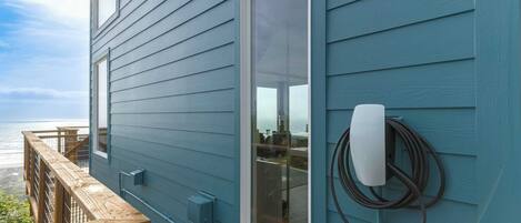 A blue house with a wooden deck overlooking the ocean.