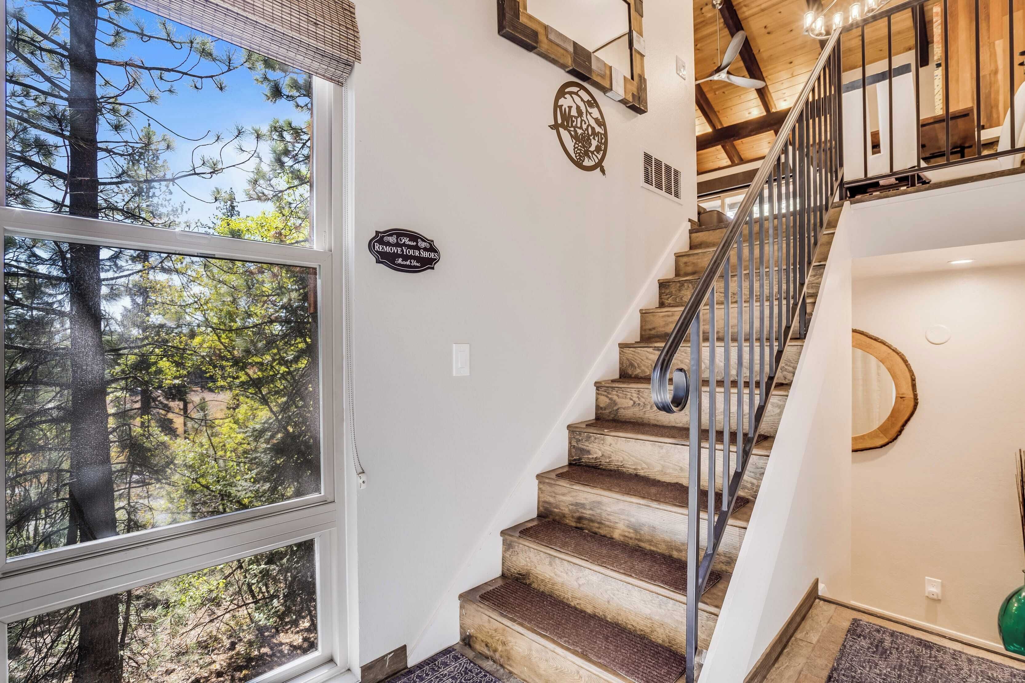 A staircase with a metal railing, wooden steps, and a 'Welcome' sign on the wall.