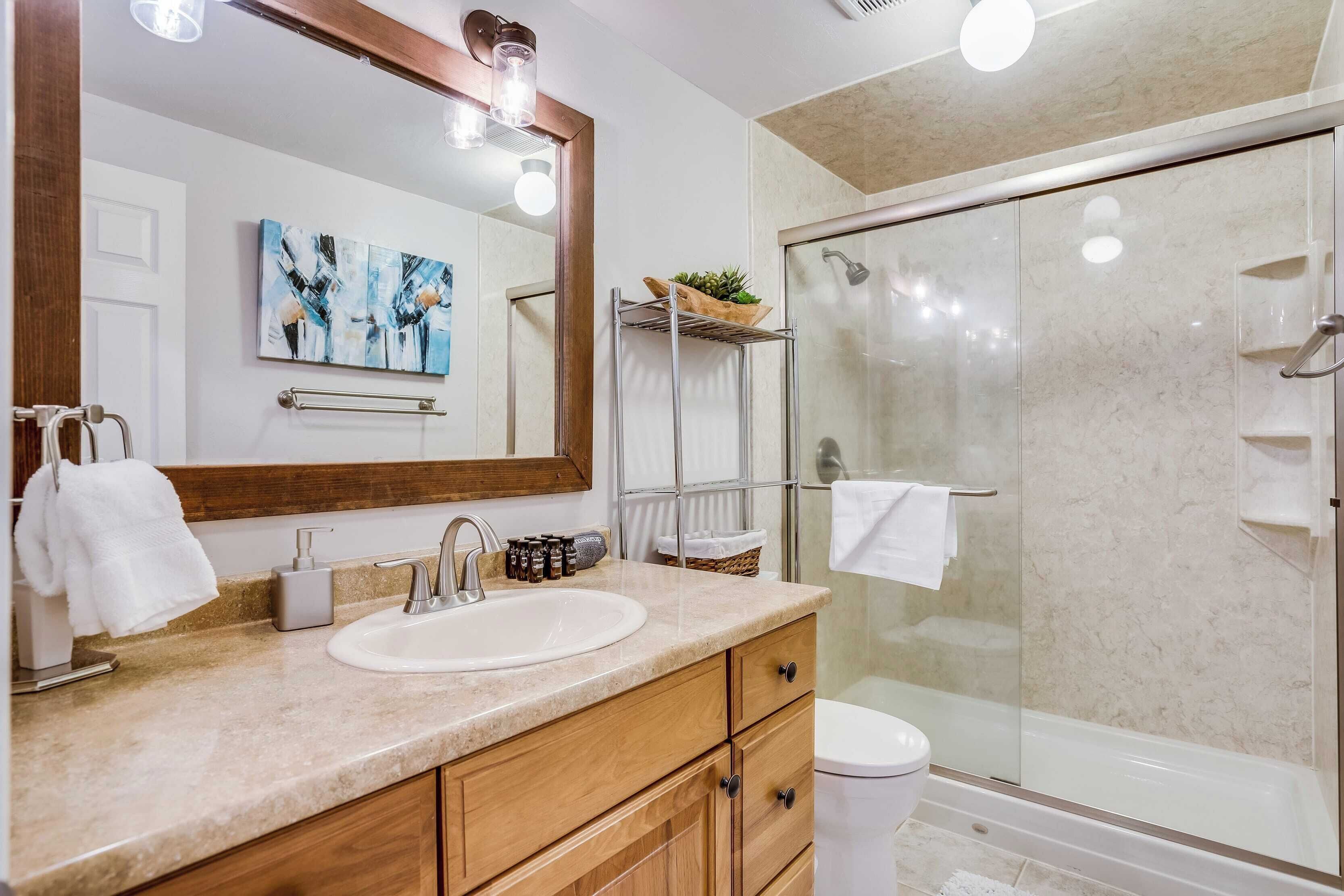 Une salle de bain moderne avec un grand miroir, un lavabo, des toilettes et une douche à parois de verre.