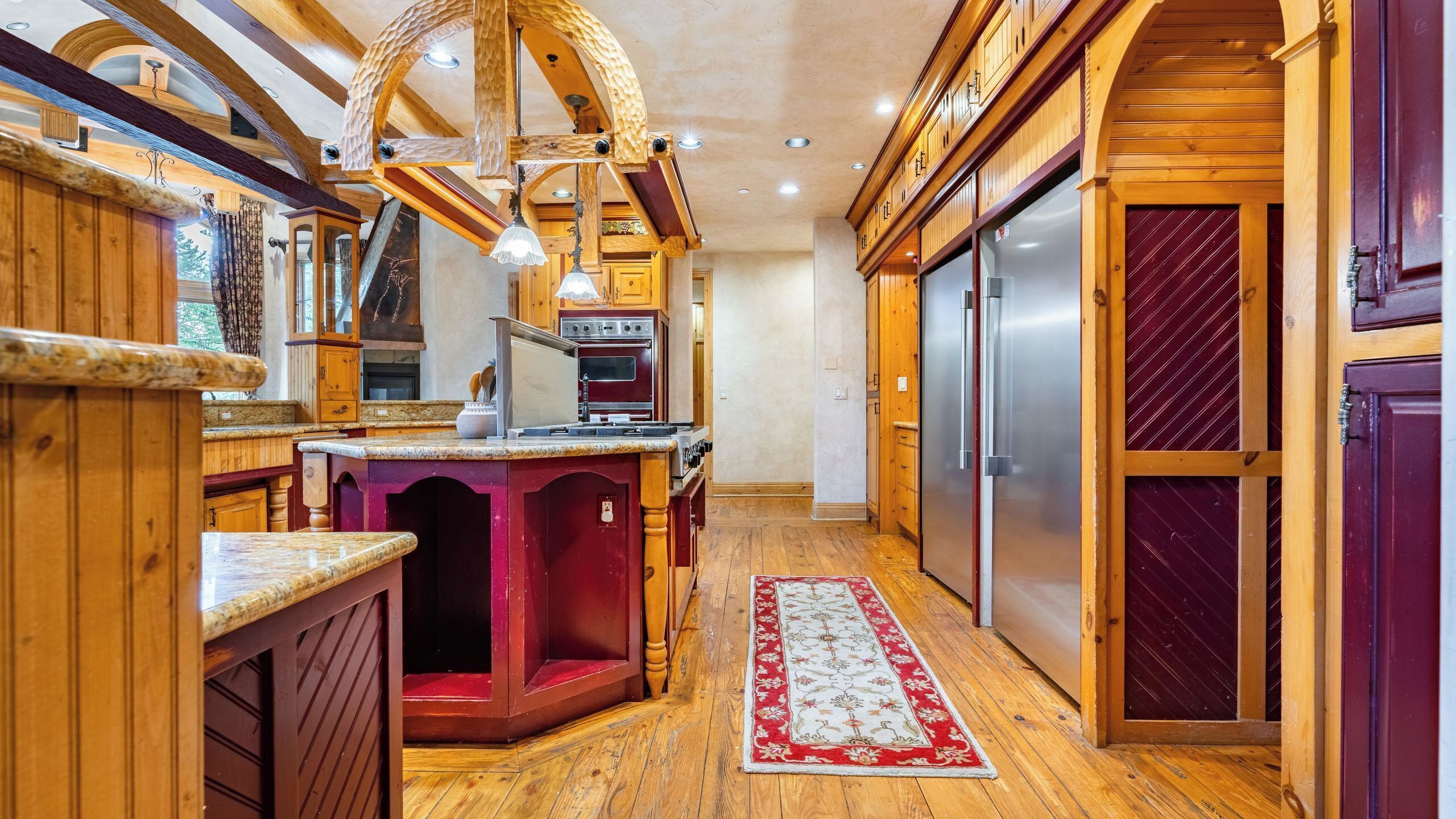 A kitchen with wooden cabinets, a marble countertop, a built-in stove, and a refrigerator.