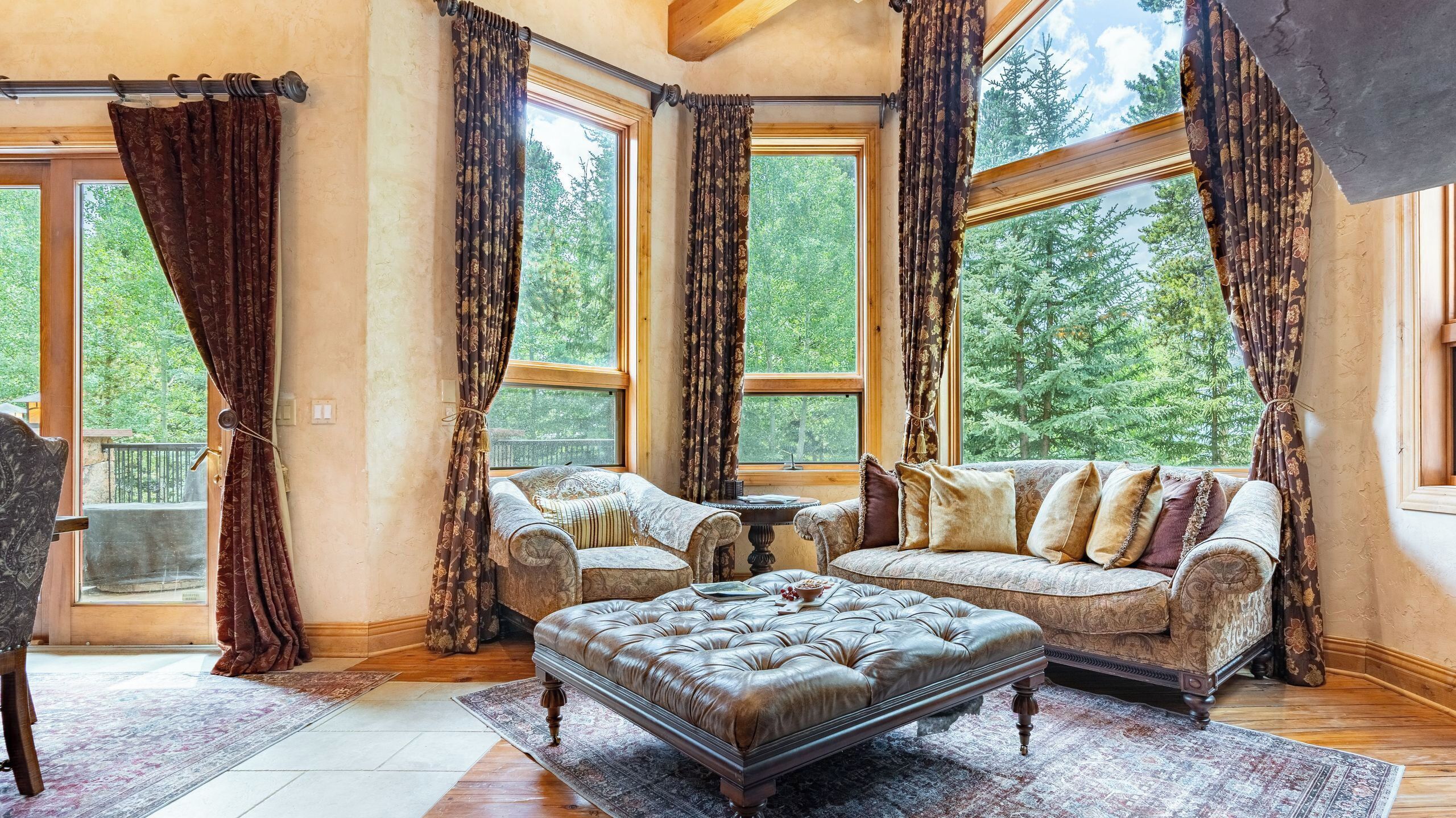 A spacious living room with a large sectional sofa, a leather ottoman, and a dining table.