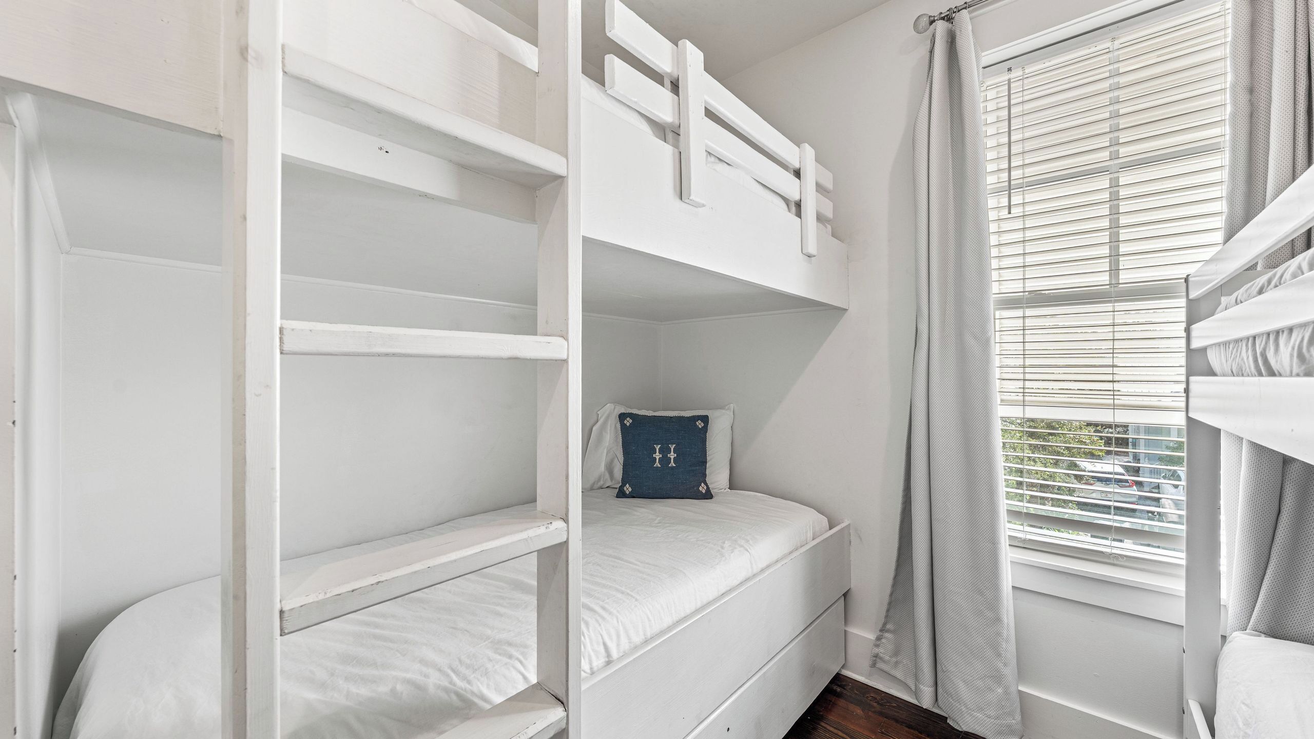 Camera con un letto a castello, una finestra e tende.
