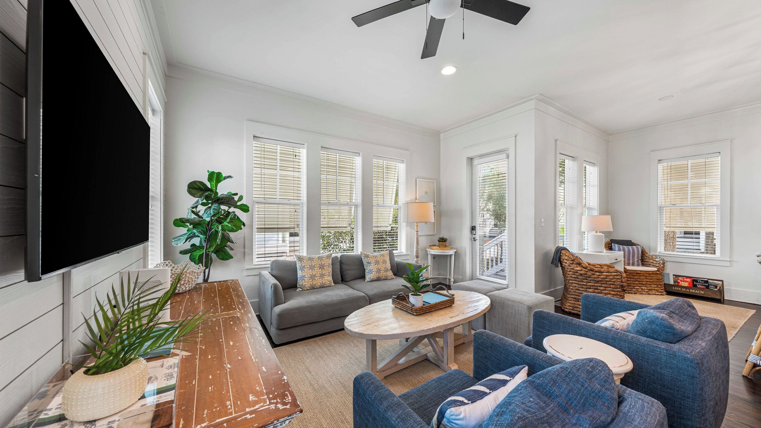 A living room with a sofa, armchairs, a coffee table, a TV, and a ceiling fan.