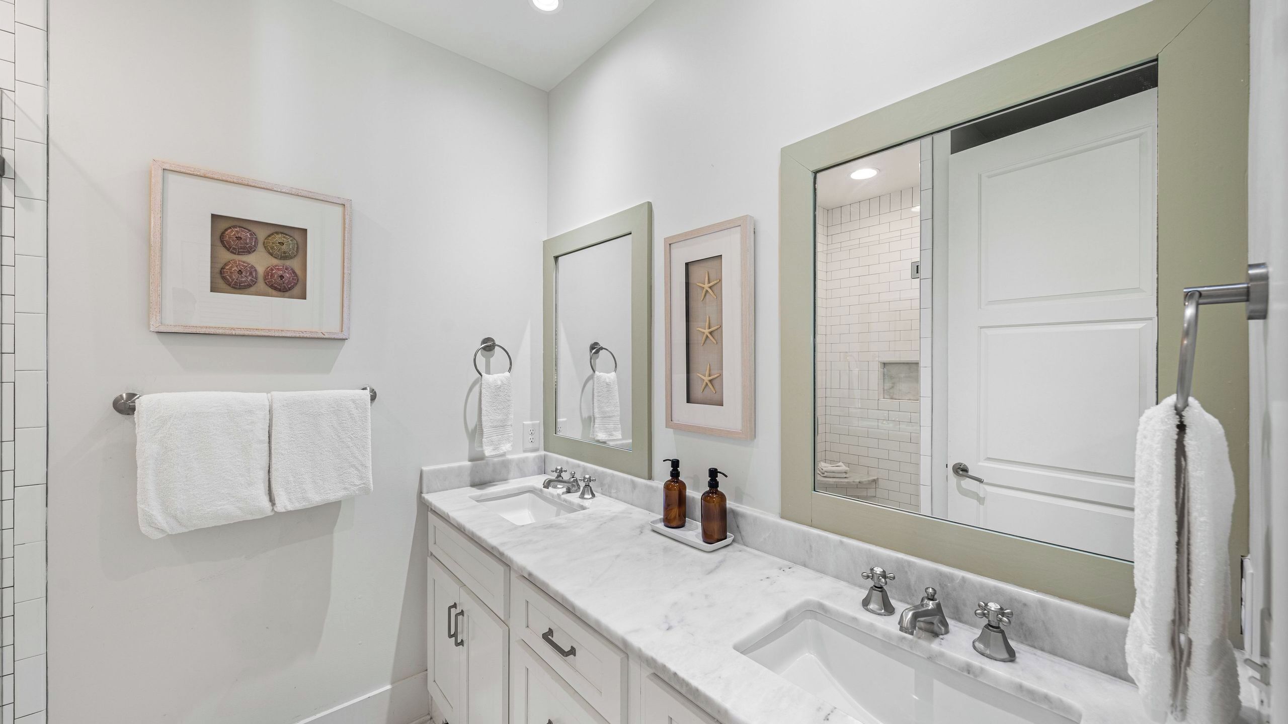 A bathroom with two sinks, a large mirror, and a framed picture on the wall.