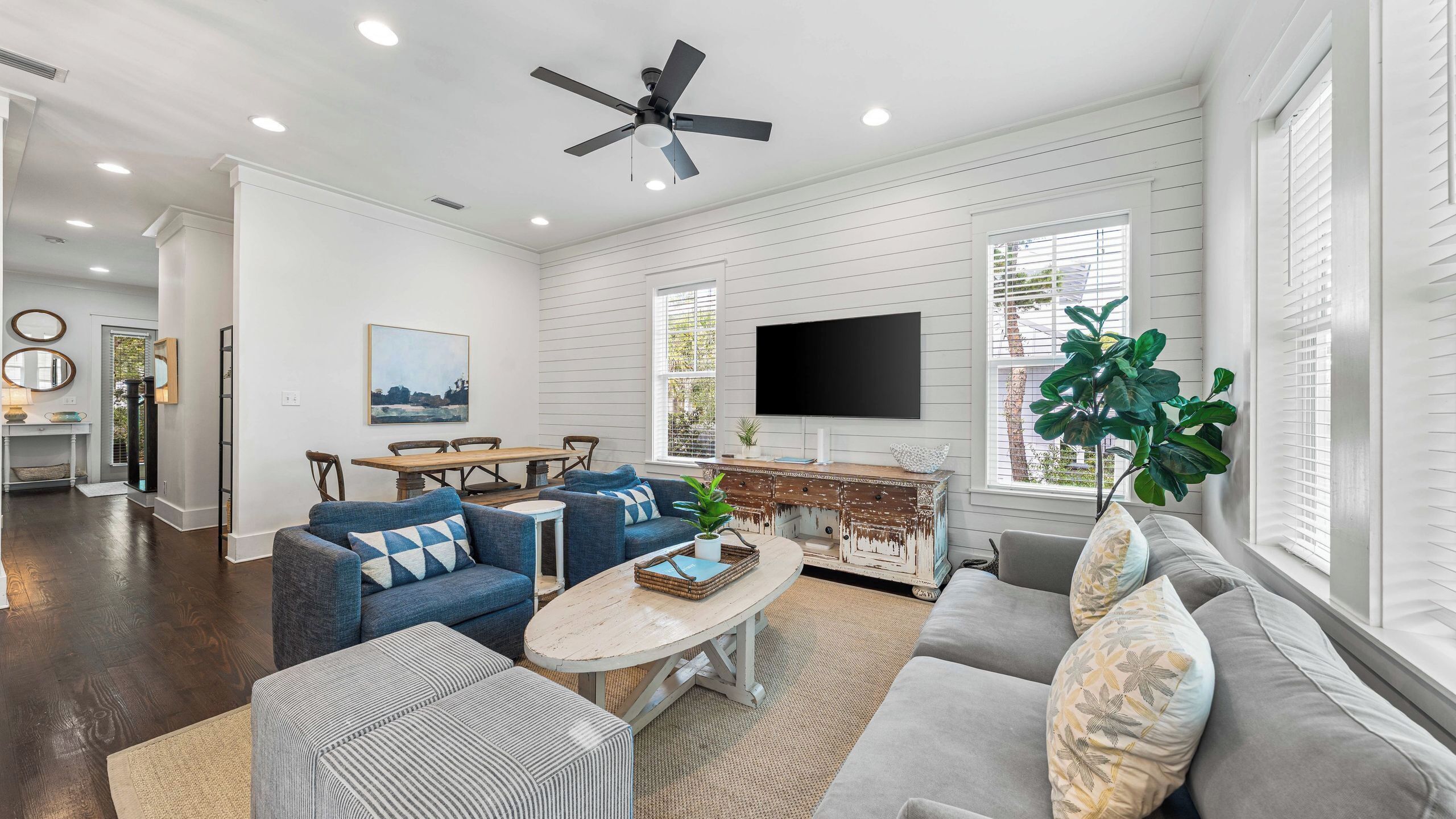A spacious living room with a ceiling fan, a TV, and a dining area with a wooden table and chairs.