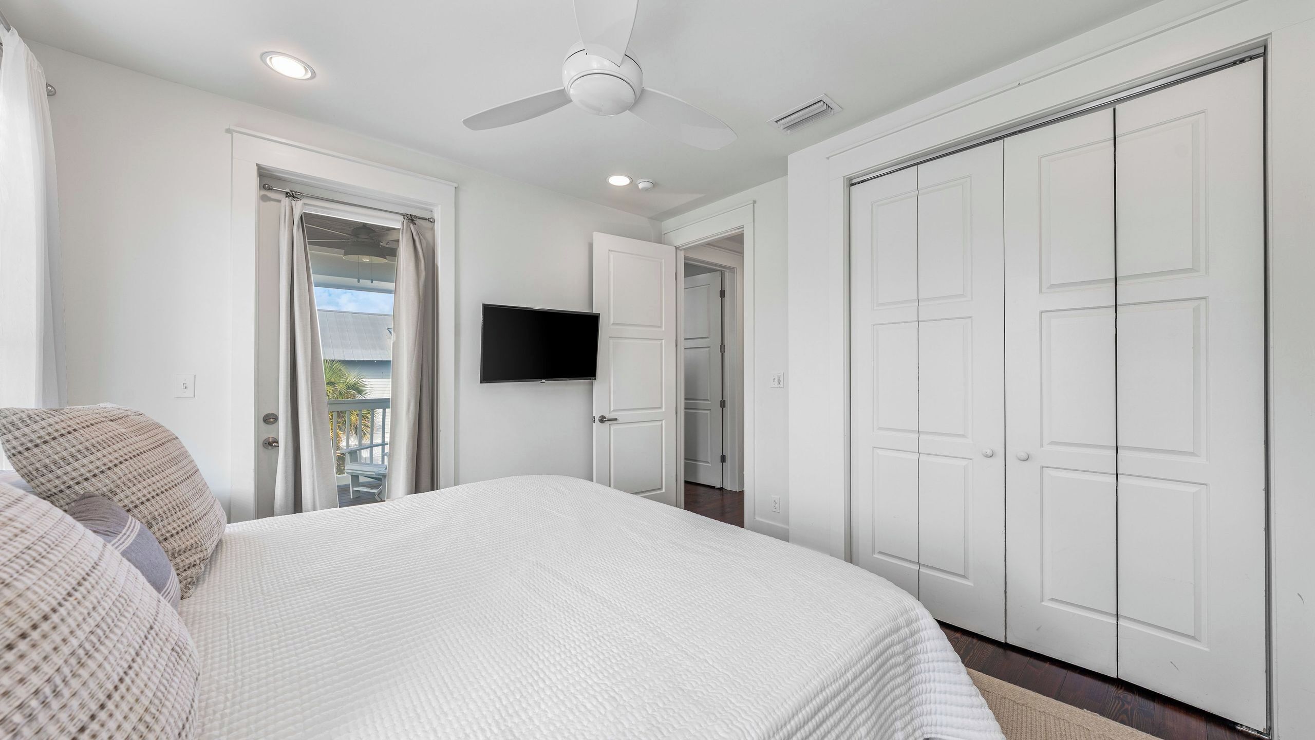 A bedroom with a bed, a ceiling fan, a TV, and a wardrobe.