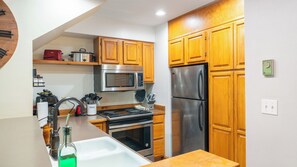 A kitchen with wooden cabinets, stainless steel appliances, a microwave, oven, and a refrigerator.