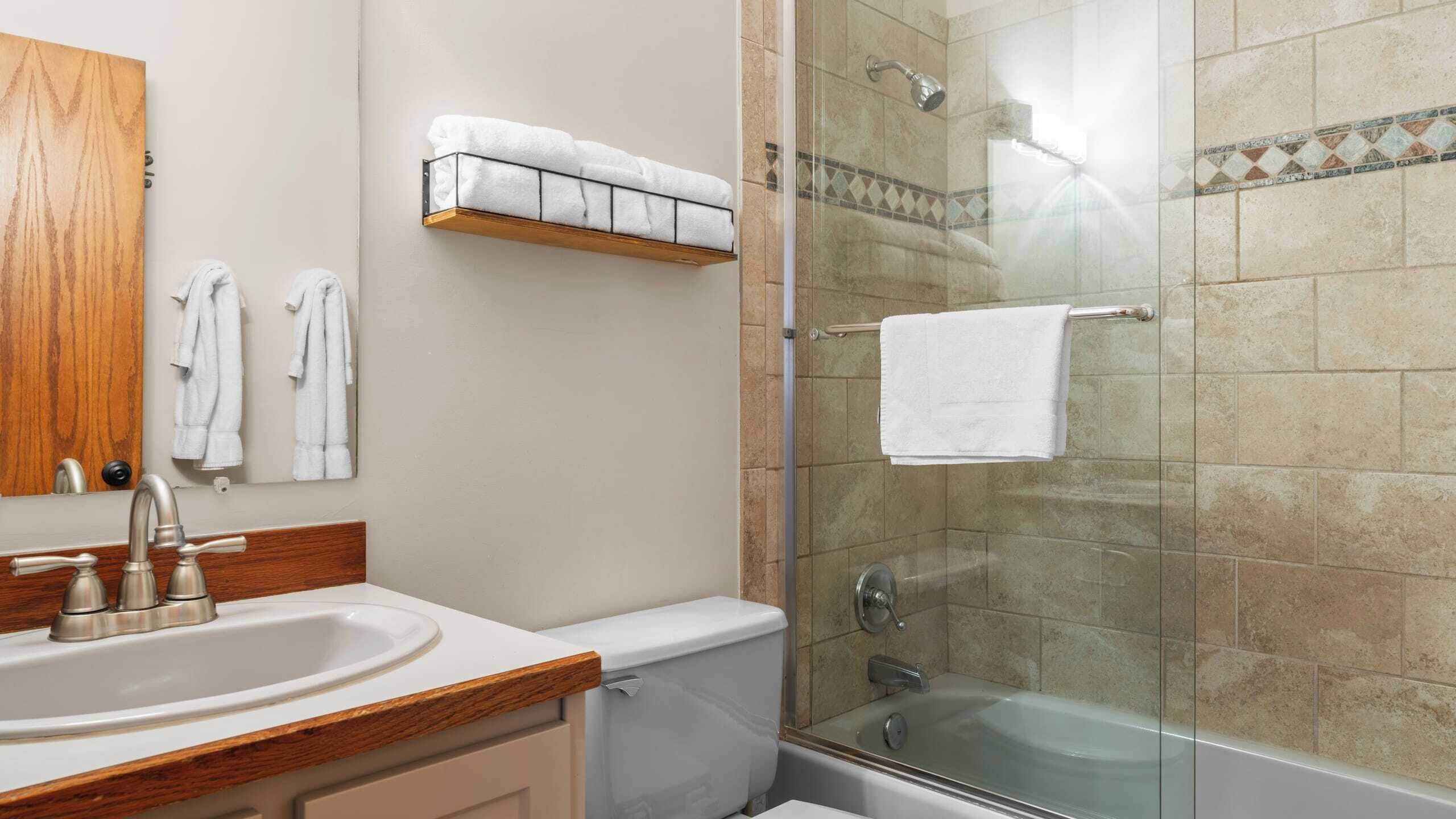 A bathroom with a wooden vanity, a glass shower enclosure, and a bathtub.
