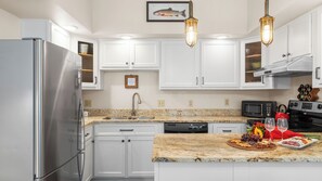 A modern kitchen with white cabinets, stainless steel appliances, granite countertops, and pendant lighting. - Ghostriders 2 by Avantstay Tidy Unit Close to the Slopes and Shops! (Telluride)