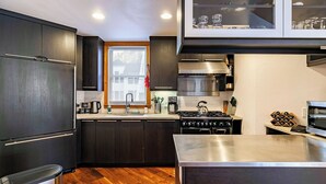 A modern kitchen with dark cabinetry, stainless steel appliances, and a window with a view. - Plunge E by Avantstay Gorgeous Townhouse in DT Telluride! (Telluride)