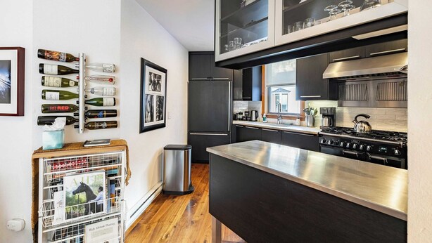 A modern kitchen with stainless steel appliances, a wine rack, and a bookcase. - Plunge E by Avantstay Gorgeous Townhouse in DT Telluride! (Telluride)
