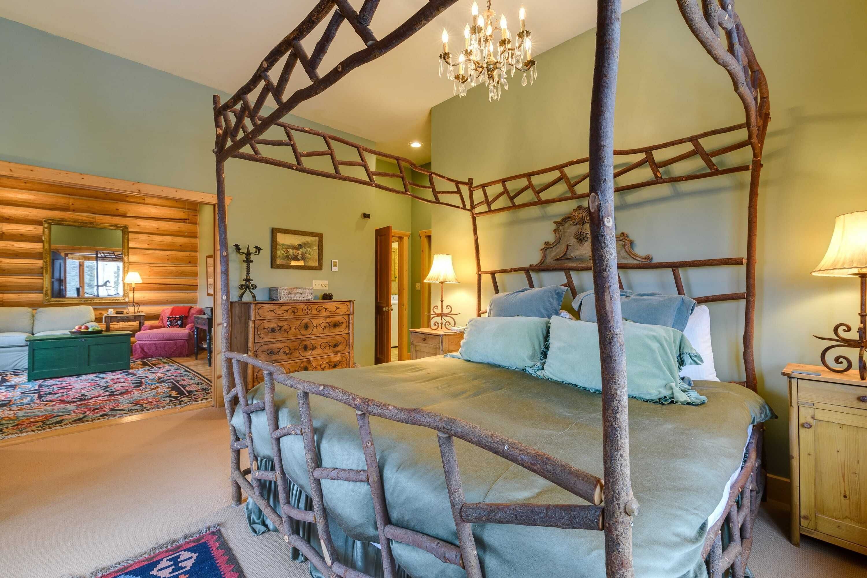 A rustic bedroom with a four-poster bed, wooden walls, and a chandelier.