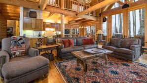 A spacious log cabin interior with a large living area, wooden ceiling beams, and a fireplace. - Snowdrift Cabin by Avantstay Breathtaking Home w/ Prime Ski Access (Telluride)
