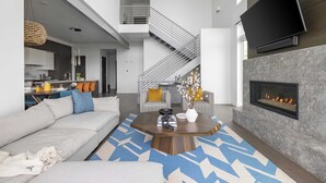 A modern living room with a sofa, coffee table, fireplace, and a staircase leading to an upper level. - Silverado by Avantstay Snowboarder's & Skiers Paradise w/ Hot Tub, Views & Easy Slope Access! (Park City)