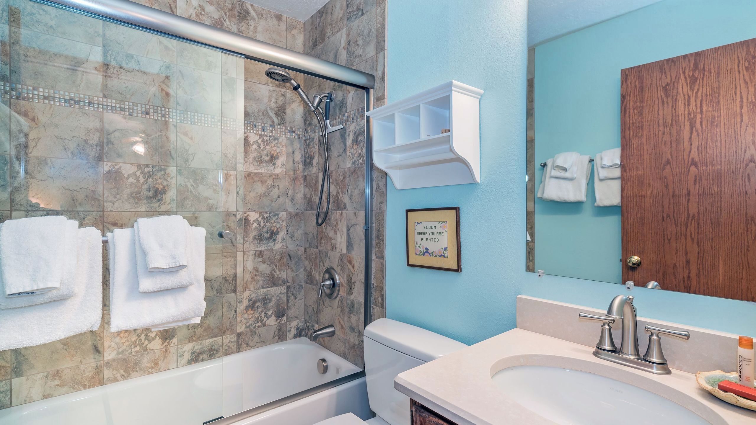 Un baño con ducha, bañera, lavamanos y espejo.