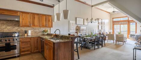 A spacious kitchen with wooden cabinets, a large island, and a dining area with a view to the outdoors.