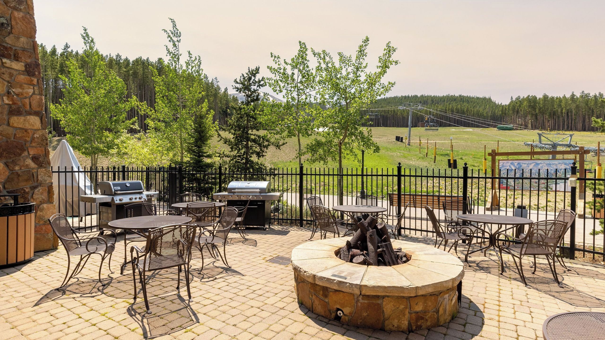 A patio with outdoor furniture, a stone fire pit, and a view of a forested area.