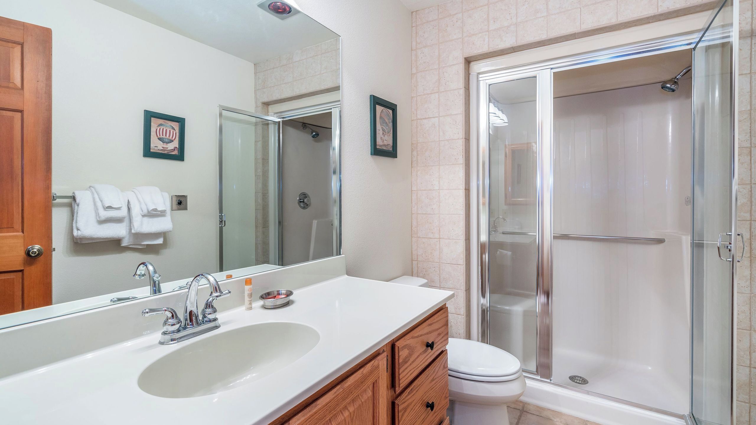 Un bagno con uno specchio grande, un lavandino, un water e una cabina doccia in vetro.