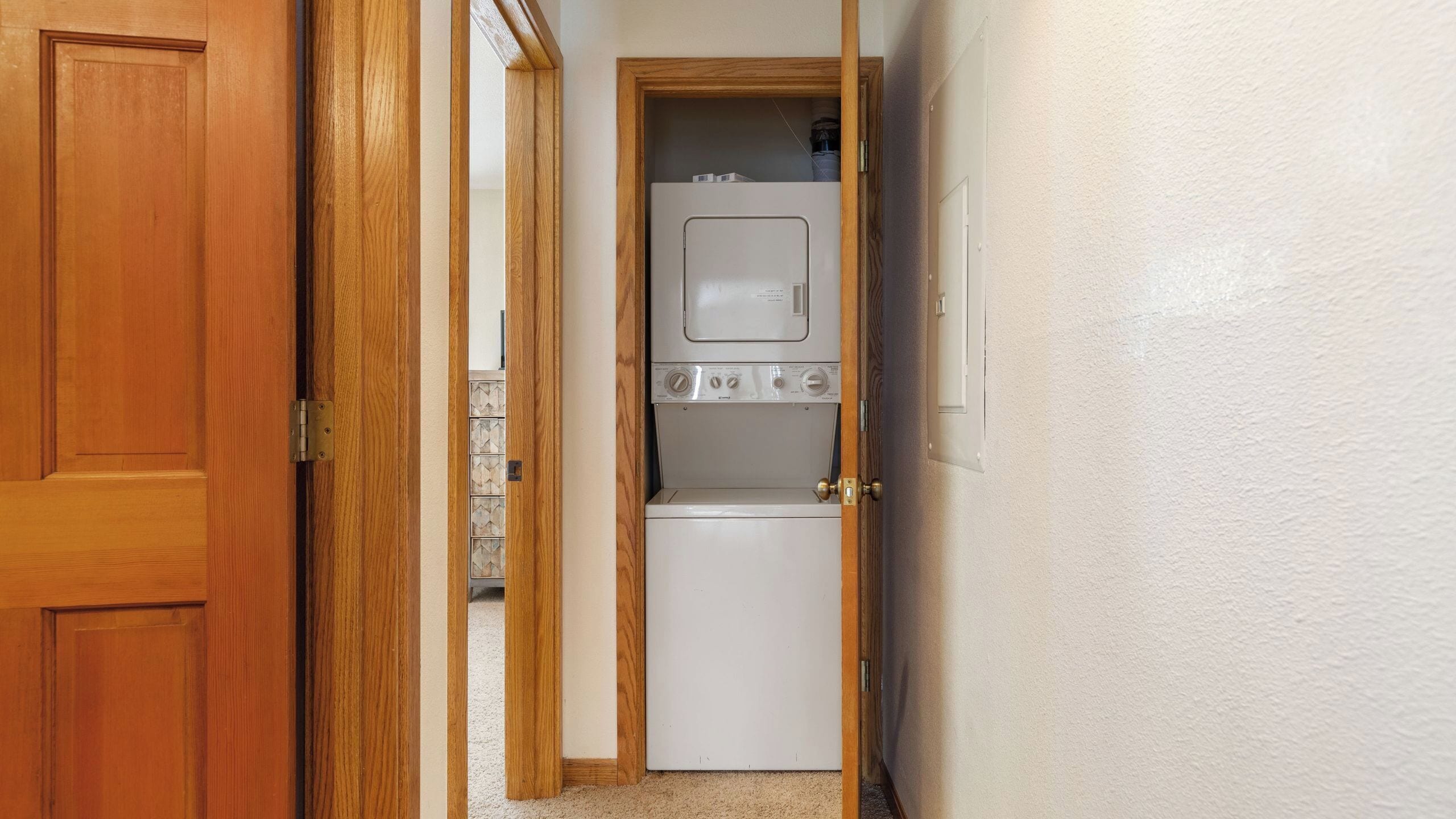 A laundry room with a washer and dryer, a wooden door, and a tiled backsplash.