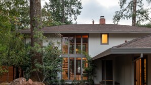 A modern house with a large glass window, a covered porch, and a stone pathway.