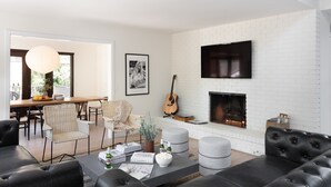 A modern living room with a fireplace, comfortable seating, and a dining area.