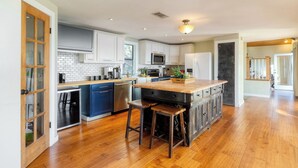 A kitchen with white cabinets, a wooden countertop, and a central island with stools. - Dawson by Avantstay Serene Austin Home set Amongst Nature w/ Pool & Close to Lake Travis (Austin)