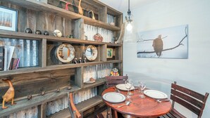 A rustic dining area with wooden shelves, a round table set for two, and a bird painting on the wall. - Cimarron Lodge 20 by Avantstay Ski In/ Ski Out Condo in Ideally Located Complex w/ Hot Tubs! (Telluride)