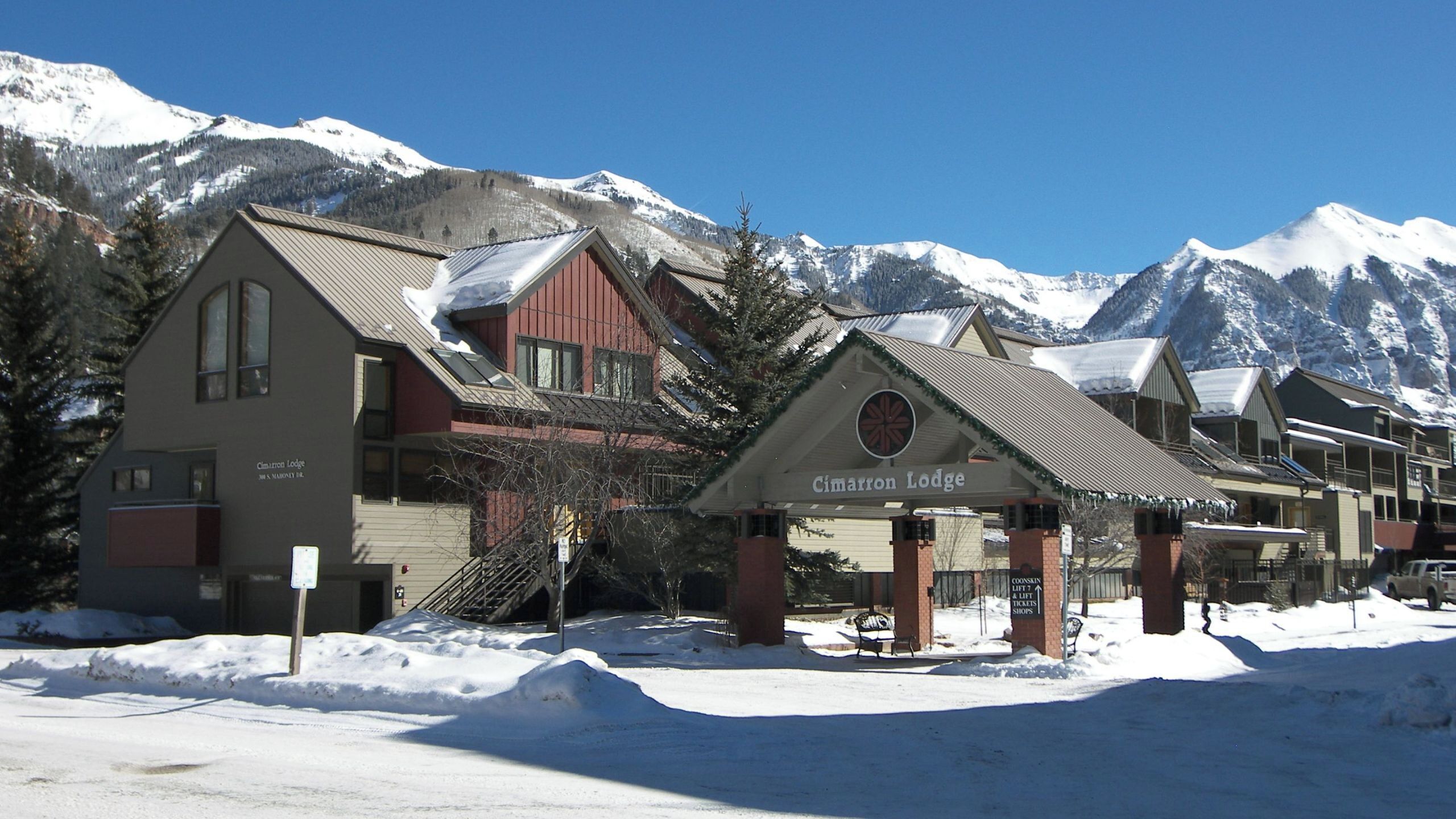 A lodge with a sign reading 'Cimarron Lodge' in front of a mountain backdrop.