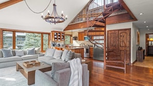 A spacious living area with a large sofa set, a wooden coffee table, and a chandelier. - Ghostriders 11 by Avantstay Top Floor Condo w/ Large Patio & Mountain Views! (Telluride)