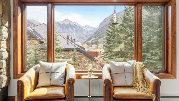 A room with two leather armchairs facing a large window with a mountain view. - Ghostriders 11 by Avantstay Top Floor Condo w/ Large Patio & Mountain Views! (Telluride)