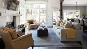 A spacious living room with a fireplace, comfortable seating, and a large window offering a view of the outdoors. - Quartz by Avantstay Stunning Home In Truckee w/ Views (Truckee)