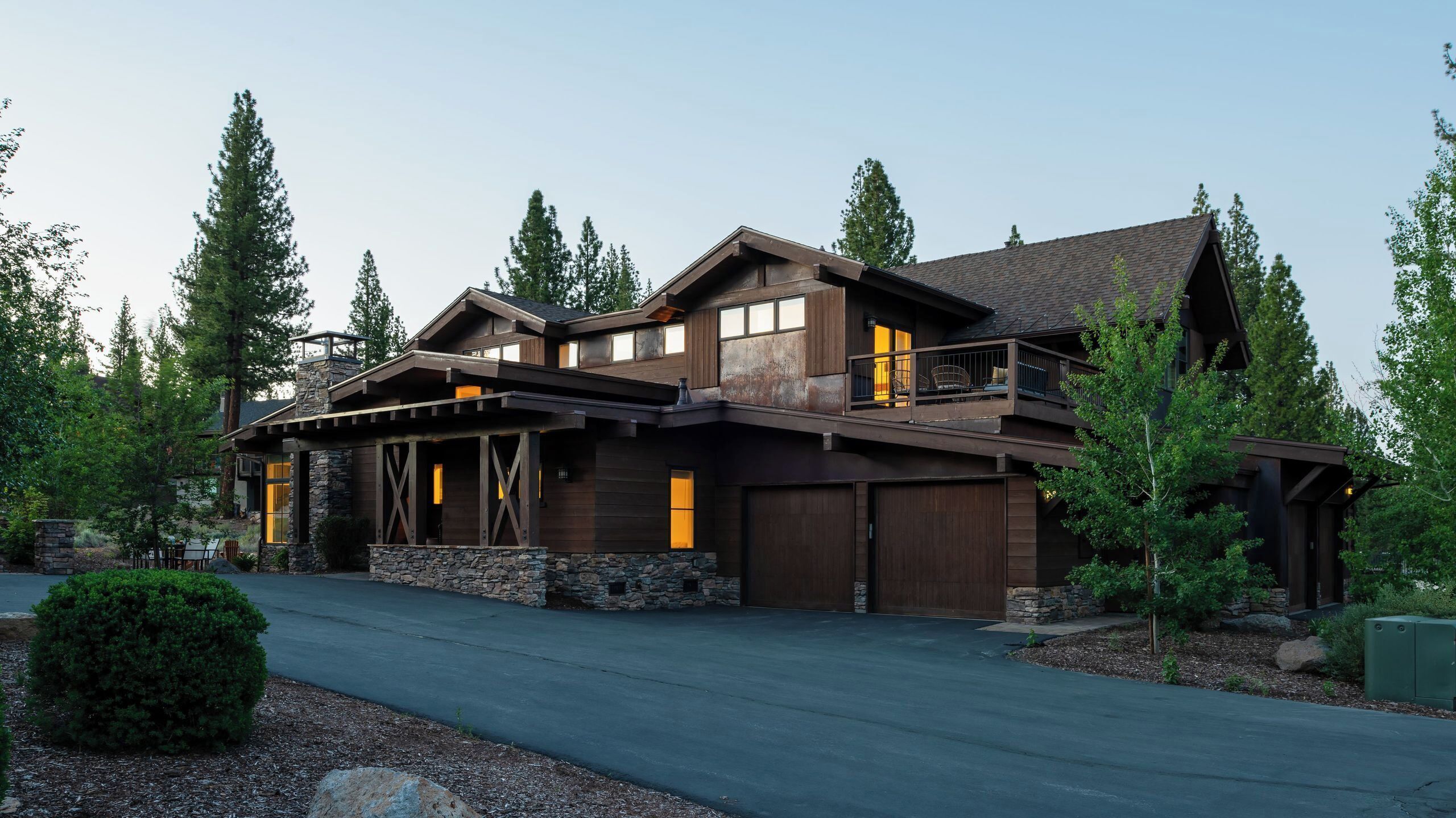 A large, two-story house with a stone foundation, multiple windows, and a balcony.