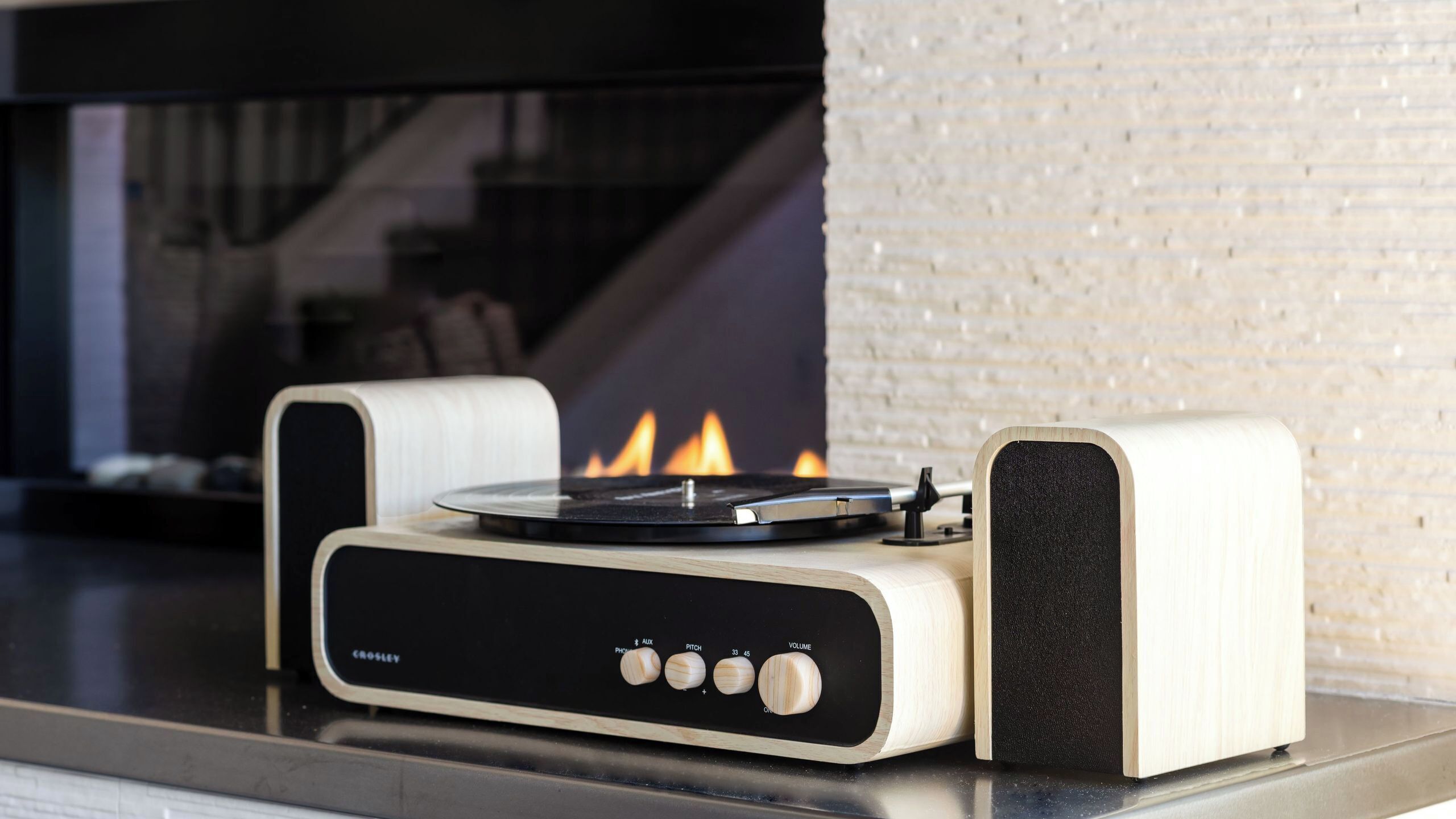 A Crosley turntable with a black and white design, placed on a modern kitchen counter.