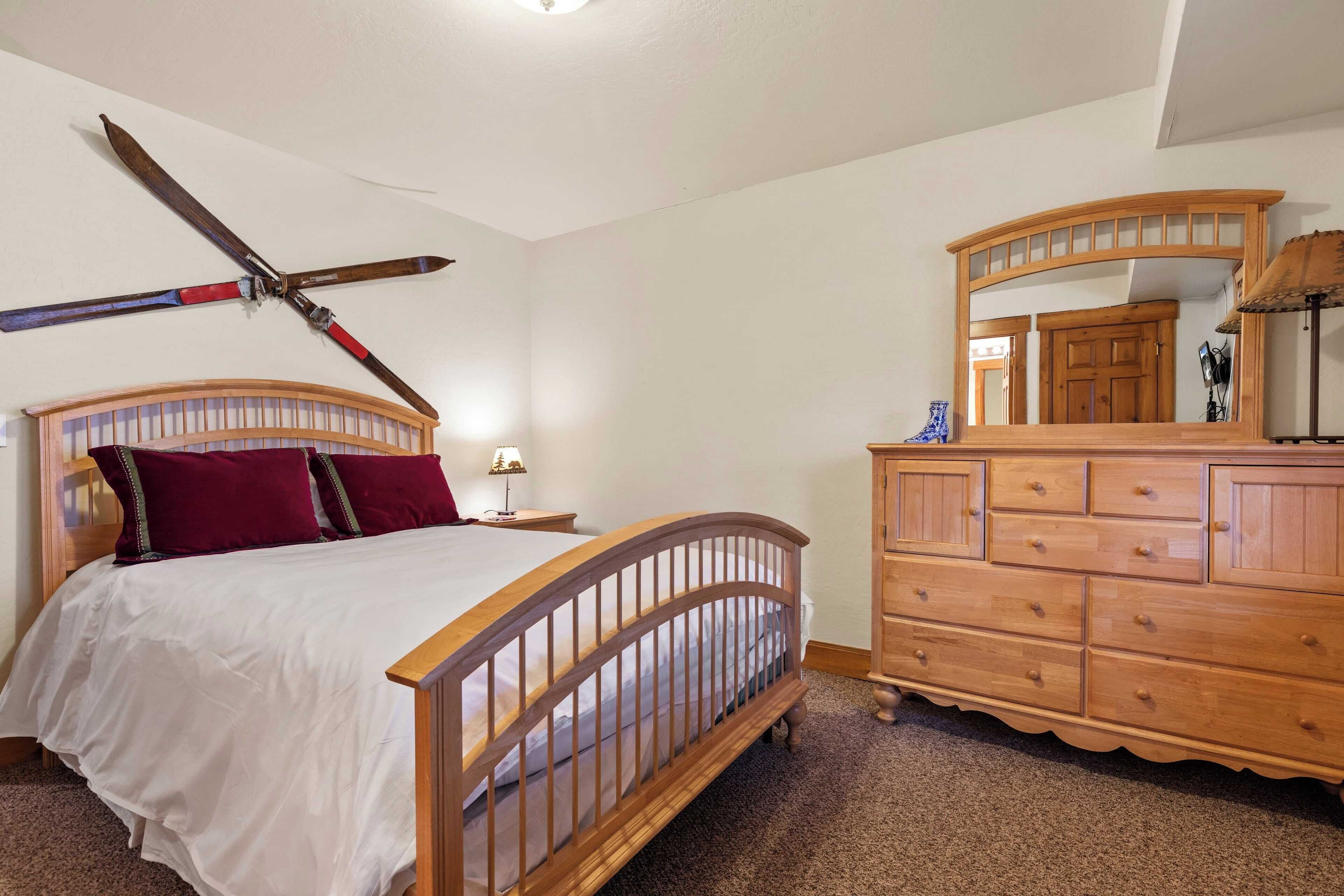 Un dormitorio con una cama de madera, un aparador y un espejo.