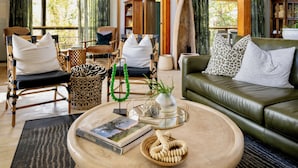 A cozy living room with a green sofa, wicker chairs, and a coffee table with books and decorative items. - Makakatana Bay Lodge (Makakatana)