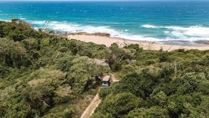 A beach with a vehicle parked on a dirt path surrounded by dense greenery. - Makakatana Bay Lodge (Makakatana)