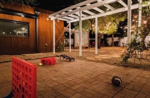 Un patio techado con pérgola, asientos y una pequeña mesa.