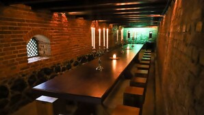 A long, narrow room with a stone wall on one side and a wooden bench along the other. There are several candles on the bench. - Hotel Fazenda Bela Vista (Dourado)