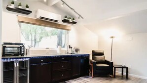 Une cuisine moderne dotée d’appareils électroménagers intégrés, d’une grande fenêtre et d’un fauteuil en cuir foncé.